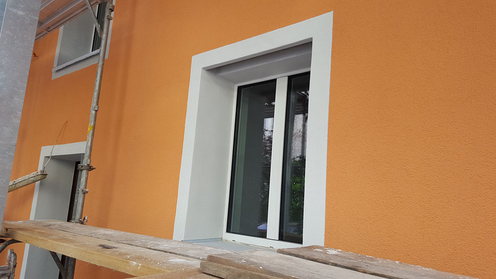Orange Fassade mit weissem Fensterrahmen auf dem Gerüst