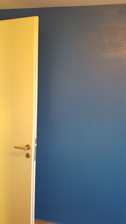Gelb gestrichene Tür vor blauer Wand